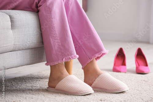 Young woman resting at home after changing high heels for soft slippers