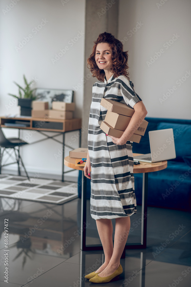 Contented online store employee holding a pile of cardboard boxes Contented online store employee holding a pile of cardboard boxes