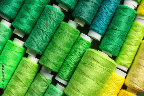 Fototapeta Spools with green threads as background