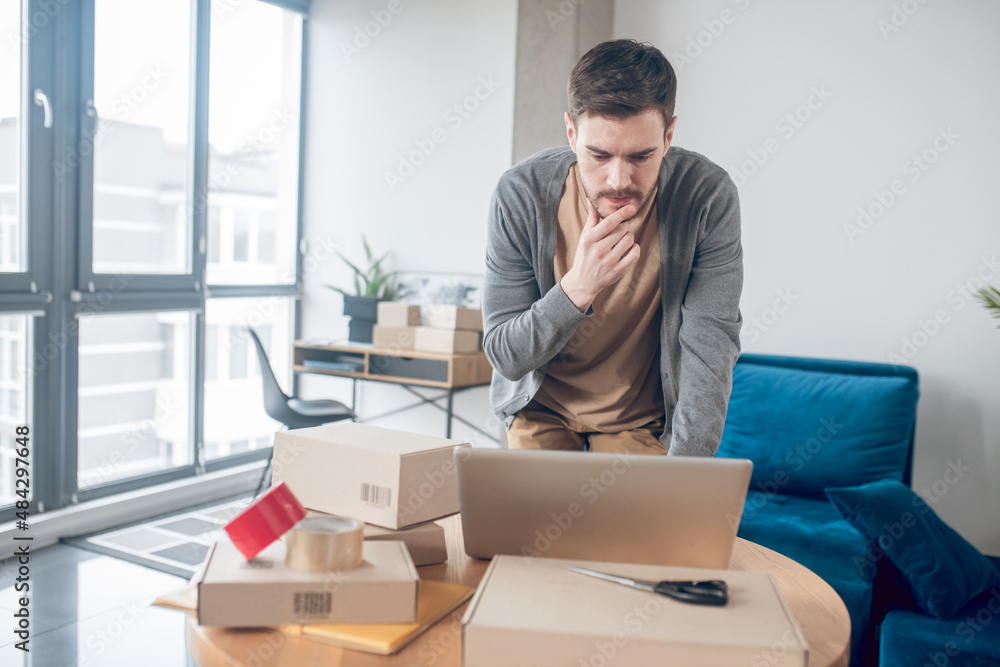 Focused Internet store employee staring at his laptop screen Focused Internet store employee staring at his laptop screen