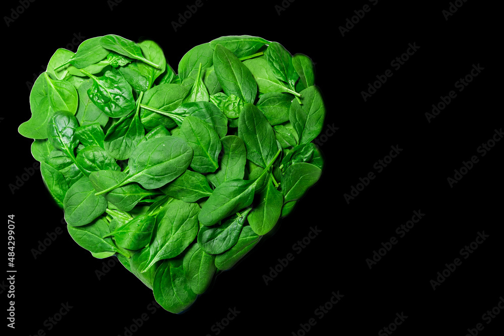 Fresh spinach, green leaves designed in heart shape with black background. Fresh spinach, green leaves designed in heart shape with black background.