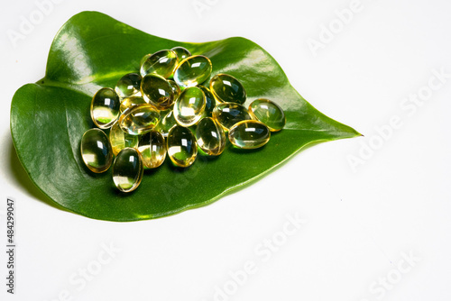 Natural vitamins and supplements on fresh green leaf with white background. photo