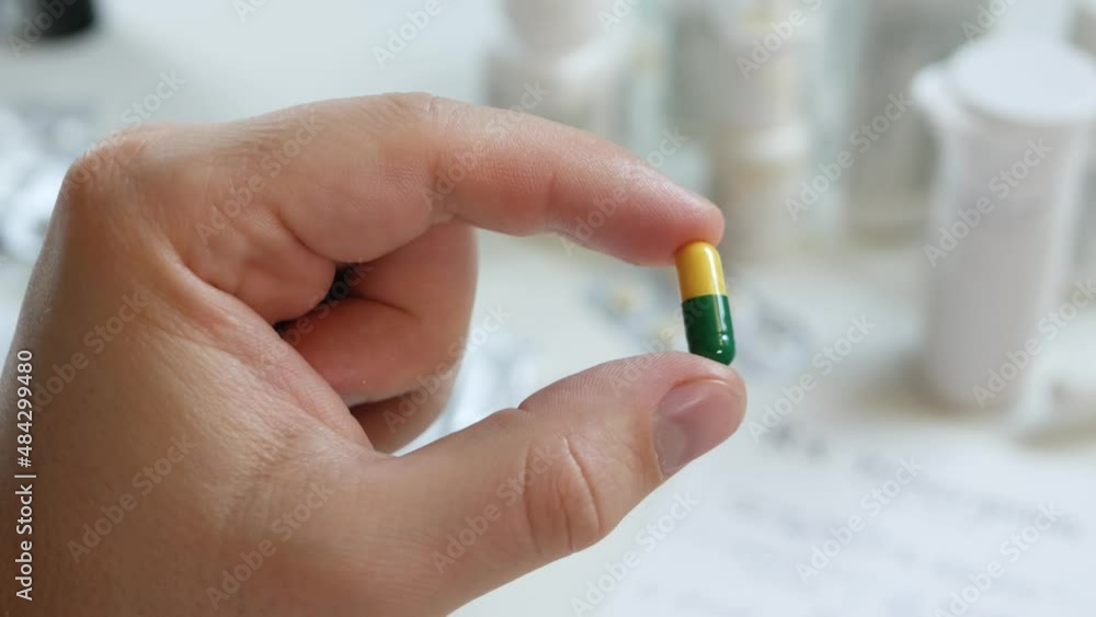 Unrecognizable male's patient hold yellow green pill. Two-piece, hard starch capsules. Health care, pharmacy and treatment concept Unrecognizable male's patient hold yellow green pill. Two-piece, hard starch capsules. Health care, pharmacy and treatment concept