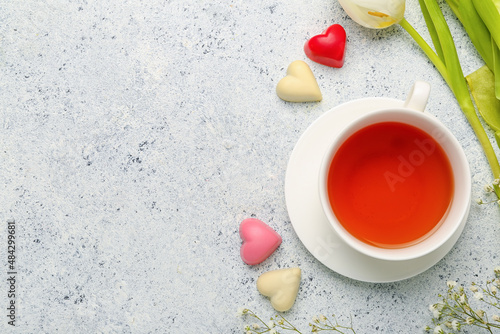 Tasty chocolate candies in shape of heart and cup with tea on light background. Valentine's Day celebration