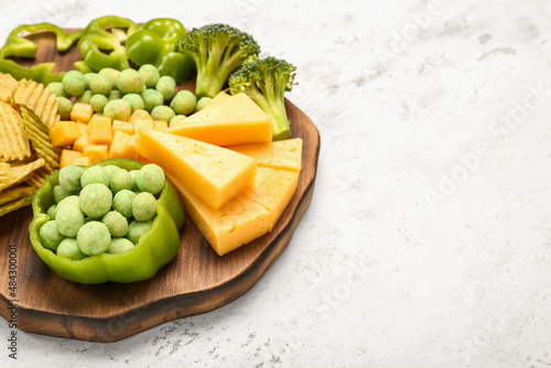 Fototapeta Naklejka Na Ścianę i Meble -  Wooden board with different snacks for St. Patrick's Day celebration on light background, closeup