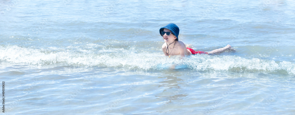 Niño chapoteando en la la costa del mar con gafas de sol