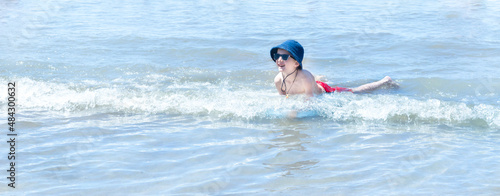 Niño chapoteando en la la costa del mar con gafas de sol