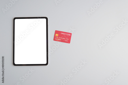 Digital tablet with blank on screen and credit card on gray background with copy space, mock up, template