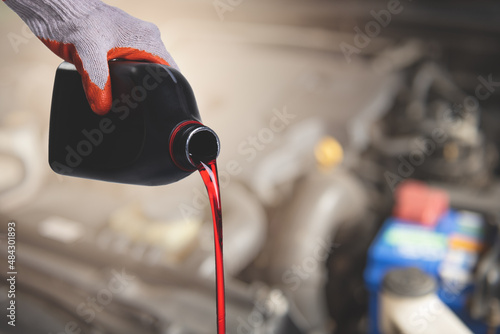 Hand mechanic in repairing car,Pouring oil to car engine on engine background