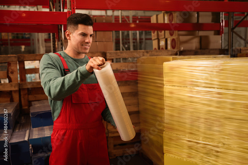 Worker wrapping boxes in stretch film at warehouse photo