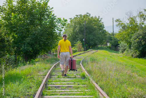 an old guy in a yellow t-shirt runs along the rails