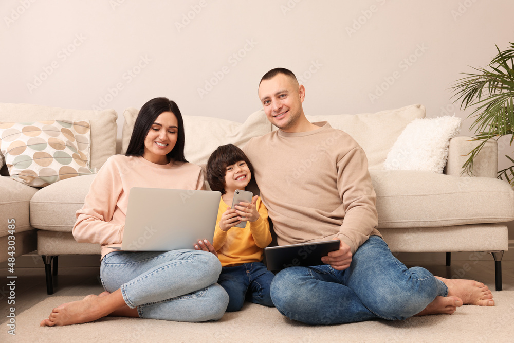 Happy family with gadgets on floor at home Happy family with gadgets on floor at home