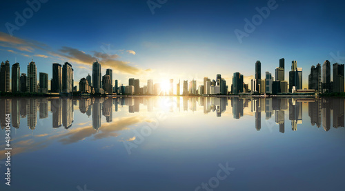 Sunset panorama of city skyline with reflection. Image composite.