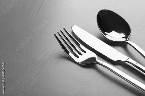 Shiny cutlery on grey table, closeup. Space for text