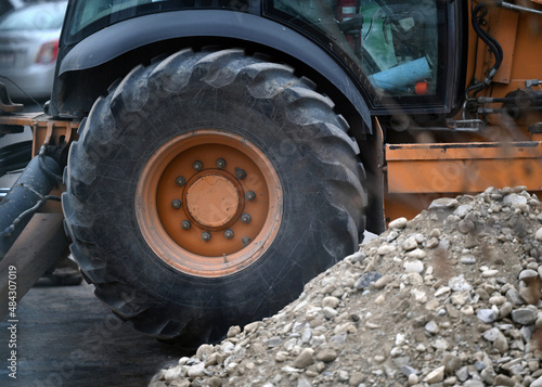 Heavy duty backhoe wheel with large rock pile at construction site