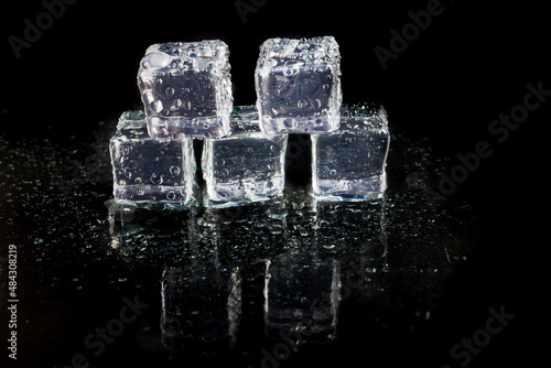 Shining ice cubes on black background. © peterkai