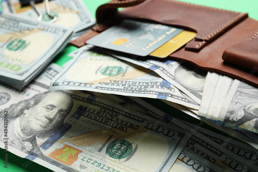 Many dollar banknotes with wallet and credit cards on green background, closeup Many dollar banknotes with wallet and credit cards on green background, closeup