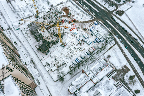 aerial view of snowy construction site in residential area. new apartment building under construction.