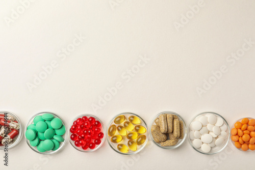 Different dietary supplements in bowls on white background, flat lay. Space for text