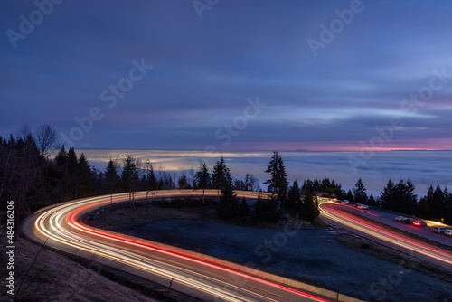 Road going up a mountain and Fog Covering the Modern City during winter sunset twilight. Canadian Nature Background. Taken at Cypress Lookout  Vancouver  British Columbia  Canada.
