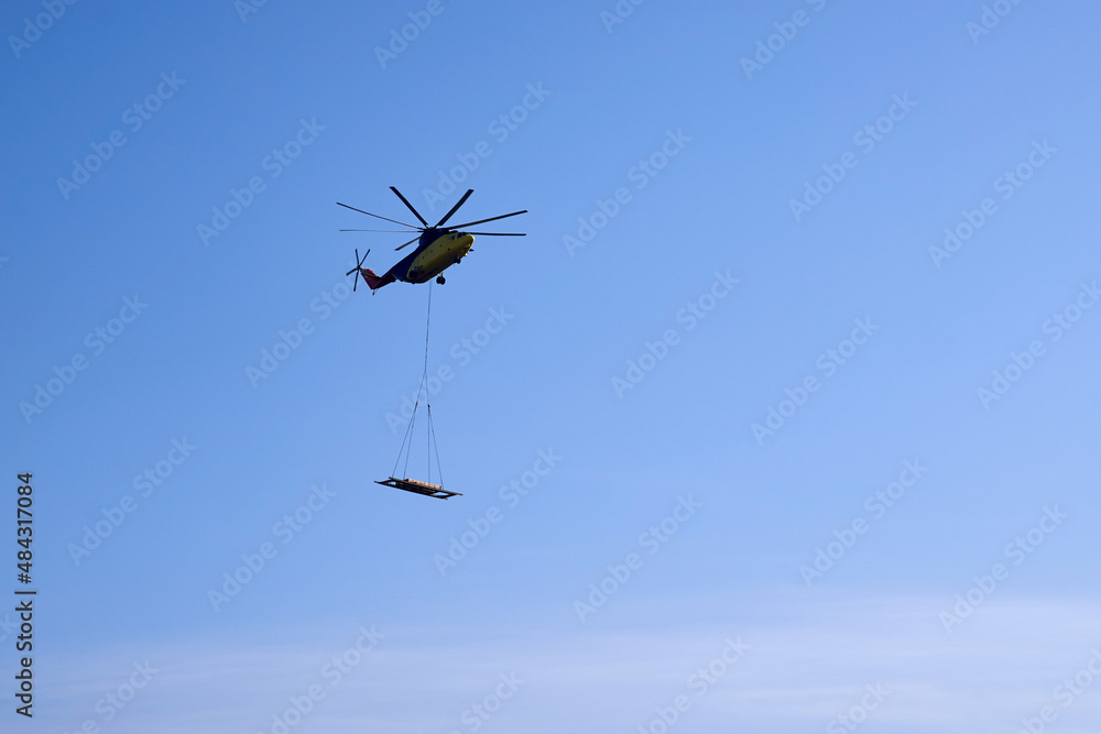 The world's largest cargo helicopter hovers overhead. Bottom view.The world's largest cargo helicopter transports cargo on a wire rope. Bottom view The world's largest cargo helicopter hovers overhead. Bottom view.The world's largest cargo helicopter transports cargo on a wire rope. Bottom view