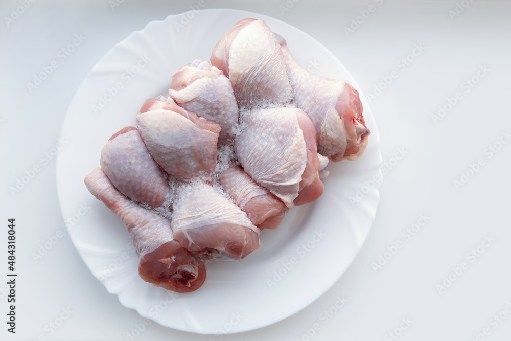 Frozen chicken legs on a plate. Defrost raw meat. Cook food.