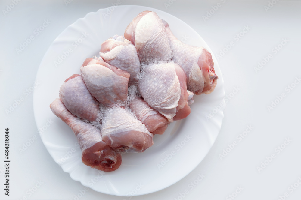 Frozen chicken legs on a plate. Defrost raw meat. Cook food. Frozen chicken legs on a plate. Defrost raw meat. Cook food.