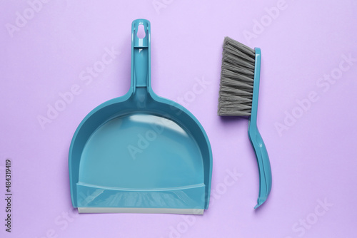 Plastic hand broom and dustpan on violet background  flat lay