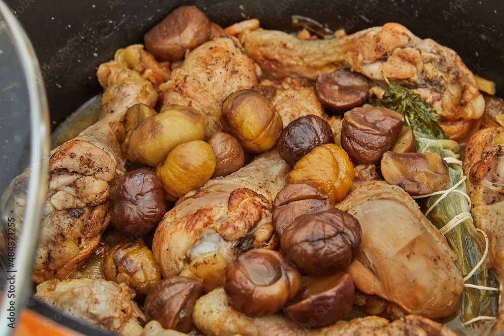 Chicken legs baked with chestnuts and mushrooms in saucepan on gas stove. French gourmet cuisine Chicken legs baked with chestnuts and mushrooms in saucepan on gas stove. French gourmet cuisine