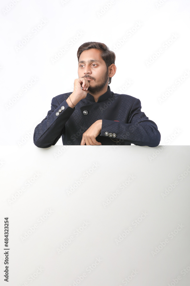 Indian man holding white board, promoting offers on festival season while wearing traditional cloths, standing over white background. Indian man holding white board, promoting offers on festival season while wearing traditional cloths, standing over white background.