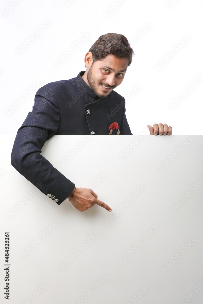 Indian man holding white board, promoting offers on festival season while wearing traditional cloths, standing over white background. Indian man holding white board, promoting offers on festival season while wearing traditional cloths, standing over white background.