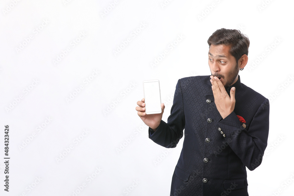 Young indian man in tradition wear and showing smartphone screen on white background. Young indian man in tradition wear and showing smartphone screen on white background.