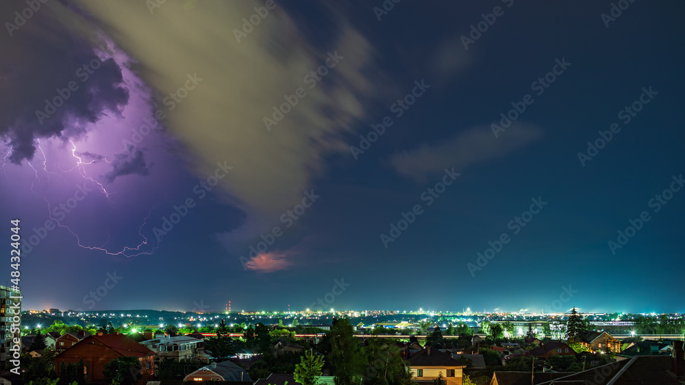 Thunderstorm over the city at night, bright lightning among dense clouds