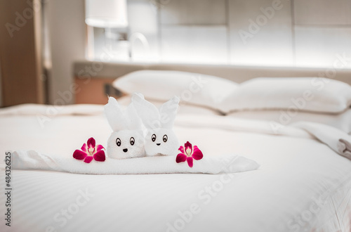 Hotel bed with towel art design shaped as a bear in a flower basket with orchids photo