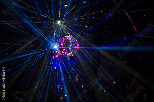 Mirrored Disco Ball and bright beams at the night party. Party attribute reflects Lazer lights. Abstract background with defocused rays. Night club atmosphere. Installation at Vilnius light festival