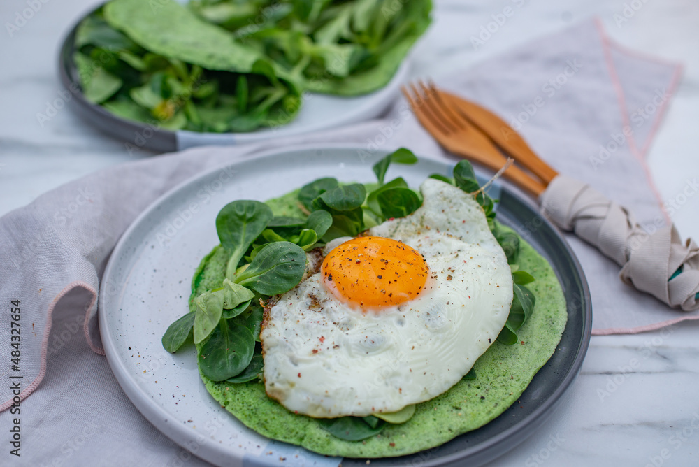 Delicious spinach crepes green colored pancake with vegetables on a table Delicious spinach crepes green colored pancake with vegetables on a table