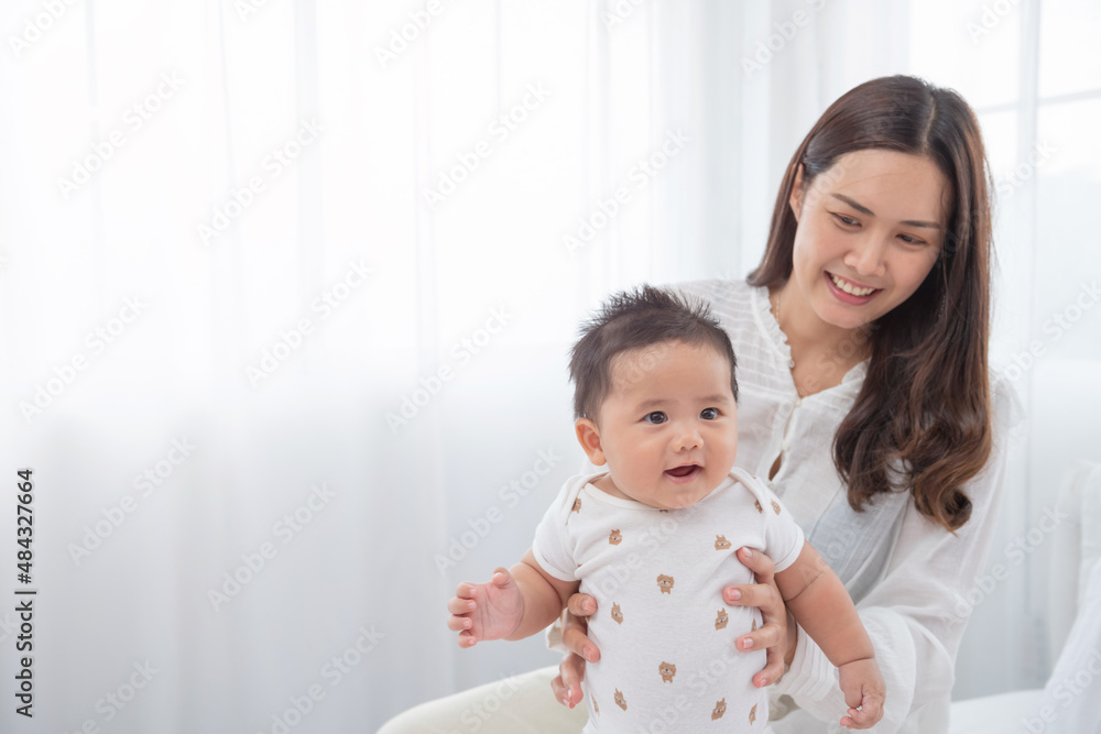 happy loving family. asian mother lifting and playing with baby in the bedroom, asia mother hug cuddle little infant or toddler, enjoy tender family moment, motherhood, childcare concept. happy loving family. asian mother lifting and playing with baby in the bedroom, asia mother hug cuddle little infant or toddler, enjoy tender family moment, motherhood, childcare concept.
