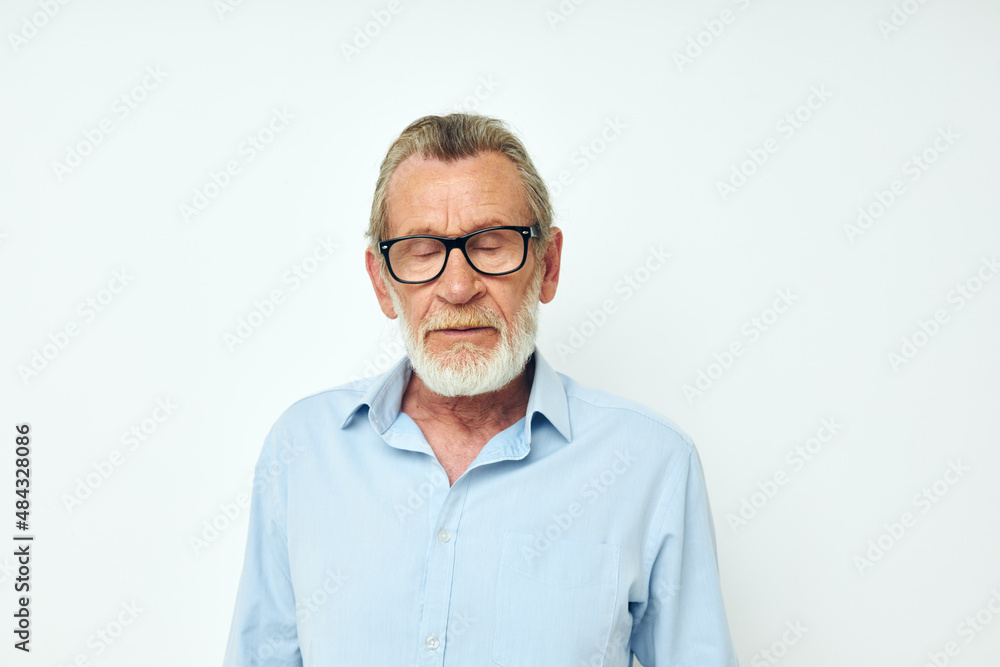 Senior grey-haired man in blue shirts gestures with his hands light background
