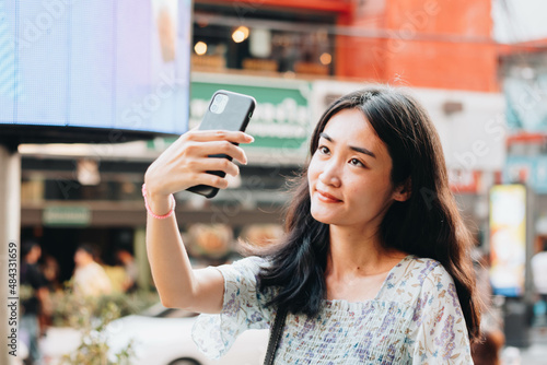 Close up of beautiful Asian woman uses a smartphone to take a selfie.