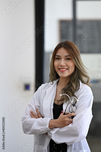 Portrait of beautiful female doctor white medical uniform holding stethoscope and smiling at camera.