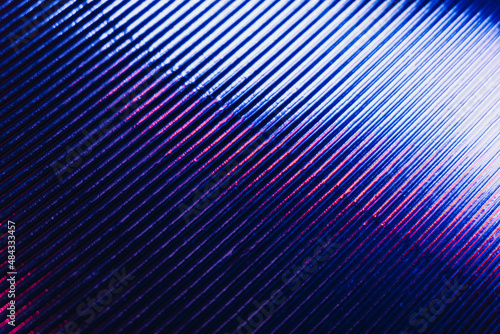 Holographic background. Ridged texture. Glowing grooved iron surface. Neon iridescent blue pink white color gradient light reflection on dark lines pattern abstract overlay.