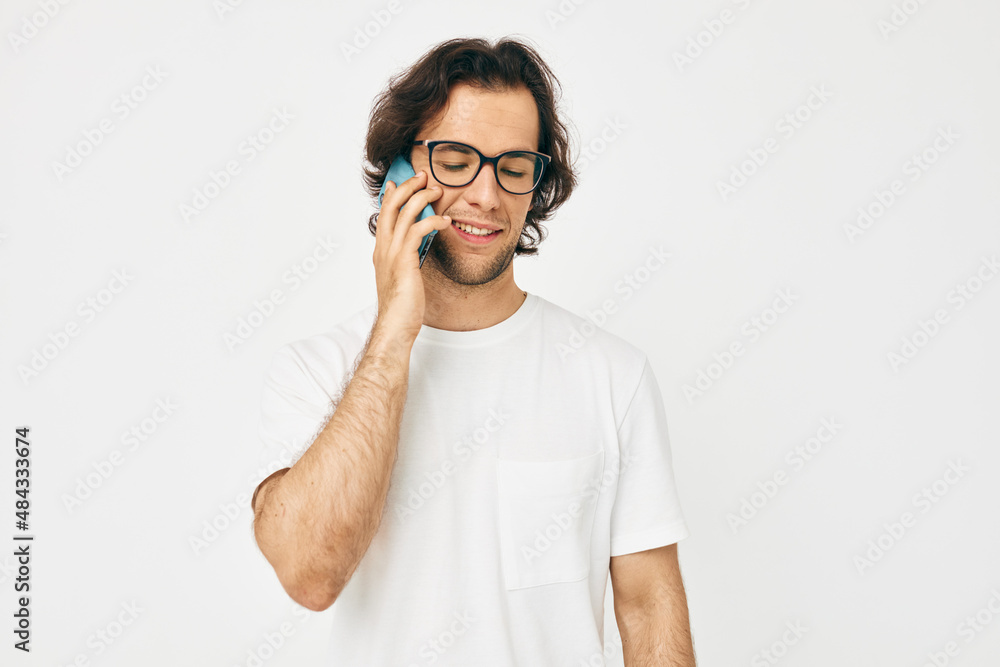 Attractive man in a white T-shirt communication by phone isolated background Attractive man in a white T-shirt communication by phone isolated background