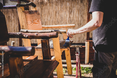 Carpenter painting wooden chairs with varnish