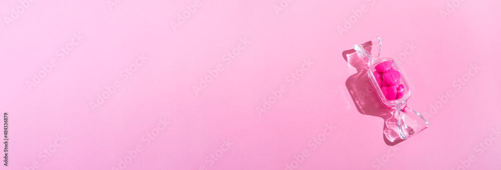 Obraz premium Transparent candy shaped box with sweet heart lollipops with hard shadow on pink background copy space. The concept of Valentines day, mothers day.