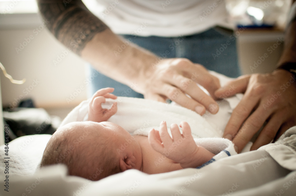 Close up of a father’s hands wrapping up his newborn baby girl with a blanket on a bed in a flat in Edinburgh, Scotland, UK Close up of a father’s hands wrapping up his newborn baby girl with a blanket on a bed in a flat in Edinburgh, Scotland, UK