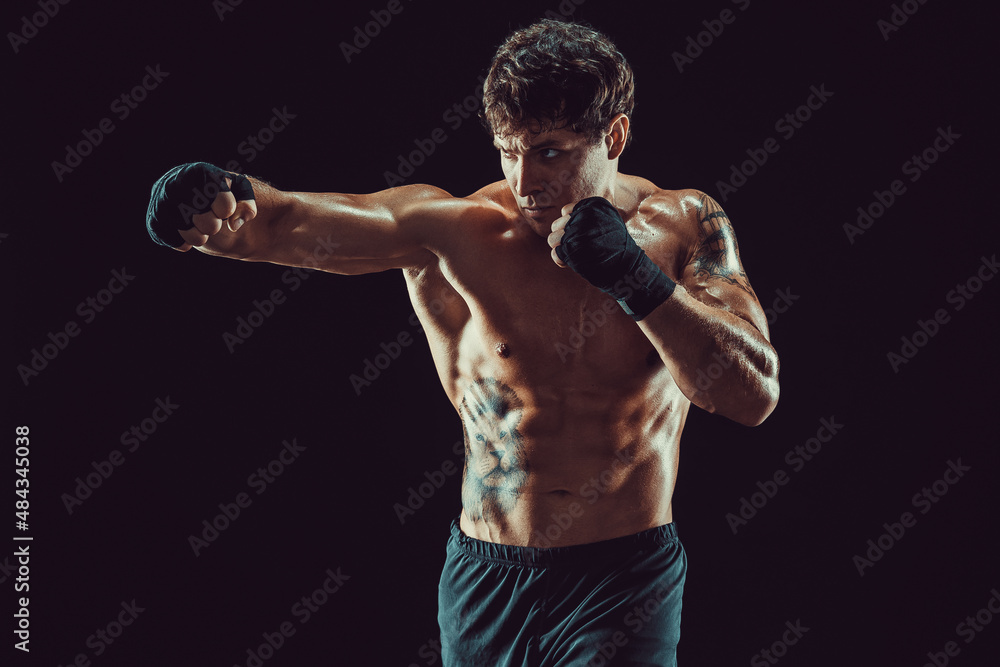 Portrait of aggressive boxer who training and practicing jab on black background. Sport concept - obrazy, fototapety, plakaty 