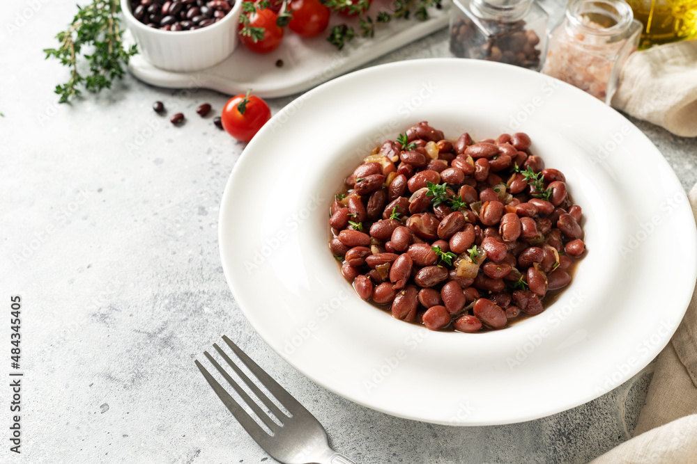 Stewed red beans with onion and thyme in tomato sauce in a white plate on the kitchen table closeup Stewed red beans with onion and thyme in tomato sauce in a white plate on the kitchen table closeup