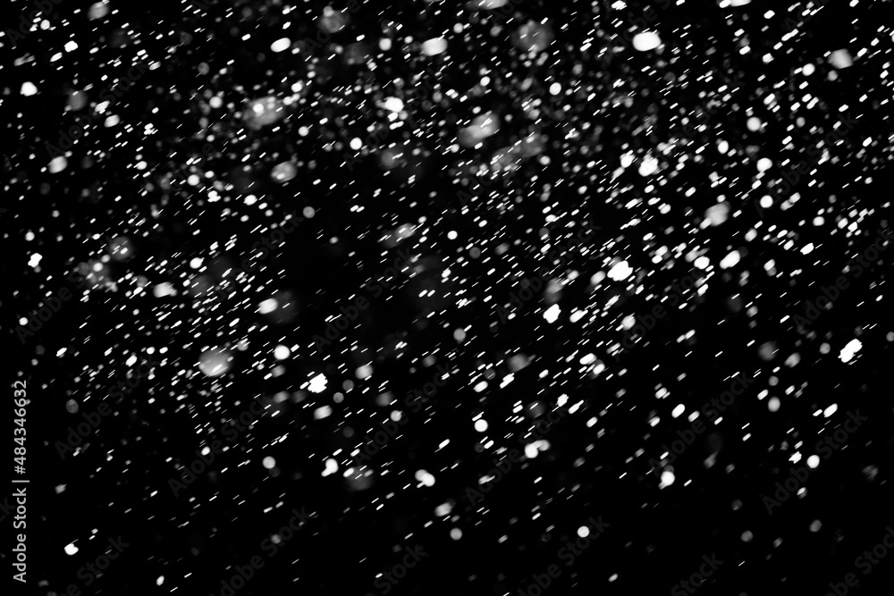 falling snow on a black background. blurred particles