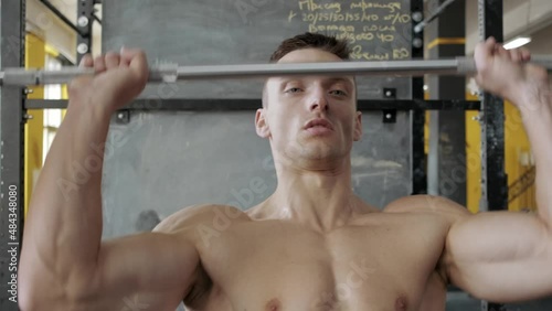 Muscular athletic man doing military bench press, overhead in the gym. Shoulders muscles workout. Sport, weight lifting and health care concept