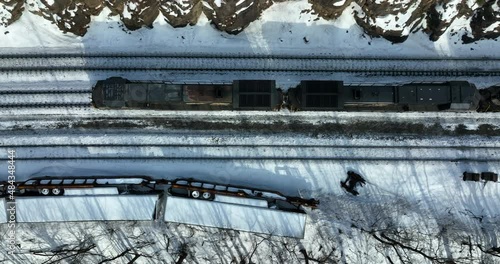 Diesel engine locomotive train car passes derailed accident on railroad tracks. Aerial winter snow view. Dangerous scene in mountain pass. photo